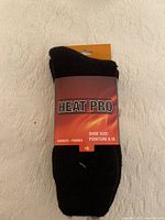 Front view of black Heat Pro sock with label indicating shoe size 6-10 and women's sizing, showing material and packaging