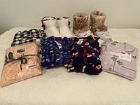 Five pajama sets and two pairs of slippers arranged on a white surface showing variety of patterns and colors.