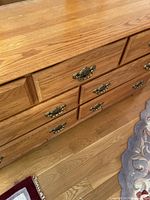 Close-up photo of oak wood drawer fronts showing brass handles and wood grain texture.