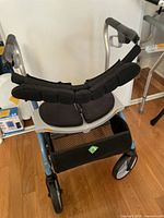 Front and top view of walker showing padded forearm supports and seating area with attached mesh storage basket.