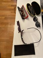 Five assorted eyewear and sunglasses with three cases on a white surface