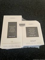 Two boxed Korres Black Pine night skin care products seen stacked, one box slightly damaged.