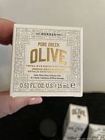 Photo showing a small white box labeled Korres Pure Greek Olive Total Eye Recovery Crème 0.51 FL OZ / 15 ml with details on product ingredients and size.