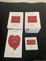 Four boxed Korres Wild Rose skincare items on a black surface: two 60ml Night creams, one 30ml oil, and one 15ml eye cream.