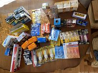 Top view showing multiple packs of light bulbs in various brands and packaging types including GE, Philips, Sylvania, and others arranged on table