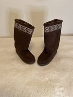 Front view of brown leather Manitobah Mukluks moccasin boots with patterned trim and plush lining.