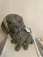 Front view of gray resin dog statue showing face and upper body with realistic curly fur texture and lifelike eyes.
