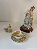 Wide shot showing all three items: figurine, tea light holder, tea cup and saucer