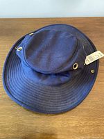 Navy blue cotton boonie hat with stitched brim and brass eyelets, laid flat showing shape and condition.