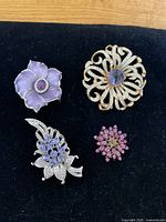 Four vintage brooches and one pair of matching earrings displayed on black fabric surface