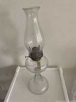 Full view of the clear glass kerosene lamp showing chimney, burner, and base.