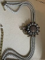 Full view of the three strand faux pearl necklace with flower centerpiece and clasp.