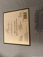 Close-up of the packaged blue cotton blanket label showing brand, material, and size information.