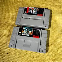 Two Super Nintendo game cartridges on yellow fabric. Top cartridge is John Madden Football, bottom is Pacific Theatre of Operations.