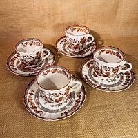 Four India Tree pattern tea cups with matching saucers displayed on textured background