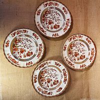 Four 8-inch plates with Spode India Tree pattern laid out showing detailed floral and bird designs with patterned borders.