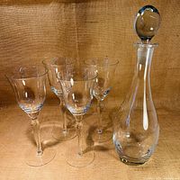 Photo showing the decanter and four matching stemmed glasses arranged together on a burlap fabric background.