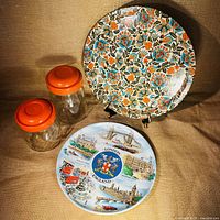 Lot layout showing two clear glass jars with orange lids and two circular souvenir trays positioned vertically and horizontally.