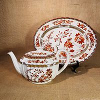 Teapot with lid and oval platter showing detailed India Tree pattern, reddish-orange and gold accents.