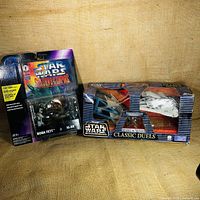 Star Wars Shadows of the Empire Boba Fett vs IG-88 action figure set and Classic Duels TIE Interceptor vs Millennium Falcon box side by side.