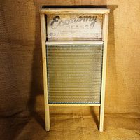 Front view of vintage washboard showing wood frame, ribbed glass scrubbing surface, and Economy Glass label on top.