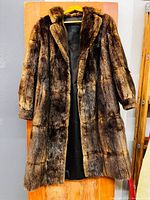 Full front view of the mid-length mink fur coat hanging against wooden door, showing the rich brown fur, length and condition.