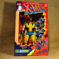 Front view of unopened Marvel Comics X-Men Wolverine Deluxe Edition action figure in original box, showing figure through plastic window with comic strip style background.