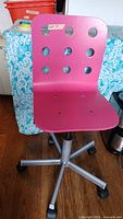 Front view of pink office chair with circular holes in the seat backrest and a silver base.