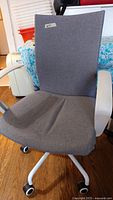 Grey fabric office chair with white armrests, showing overall condition and upholstery detail.
