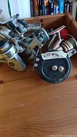 Fishing reels and rods in assorted used condition with scratches and dents, some reels have line still attached, lot tagged as #16.