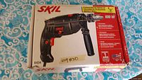 Box of Skil 600W hammer drill showing product details and branding.