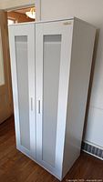 Exterior view of the white IKEA wardrobe showing two doors with frosted glass panels and simple white handles.