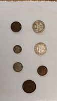 Top view showing all seven Newfoundland coins of varying denominations and colors arranged on white paper.