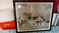 Front view of framed print depicting a village house scene