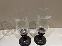 Pair of etched glass hurricane candle holders with silver plate bases on a white surface.