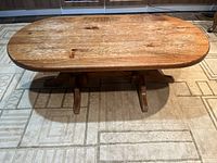 Front view of the oval pine coffee table showing the top surface wear and pedestal leg base.