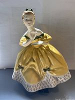 Front view of the Royal Doulton 'The Last Waltz' figurine, showing the detailed yellow dress, green bows, and facial features.