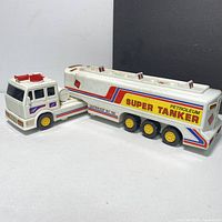 White and red battery-operated petroleum super tanker toy truck with colorful decals and multiple wheels shown from side angle.
