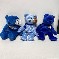 Three plush bears in blue shades positioned side by side on white background