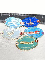 Photo of 5 Canadian aviation pins arranged in two rows with ruler showing approximate sizes, featuring colorful enamel designs of airplanes and Canadian flags.