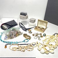 Full view of the jewelry assortment with rings, cufflinks, necklaces, sunglasses, pocket watch and case