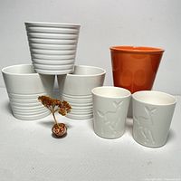White and orange ceramic planters grouped showing different styles and embossed detailing