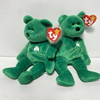 Two green TY Beanie Baby bears with shamrocks embroidered on chest, sitting against white background. Both have tag protectors attached.