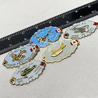 Five vintage Canadian District A-11 aviation pins laid out on a white surface with a measurement ruler above showing size. Each pin has different city and year inscriptions with Canadian flags and plane images.