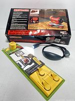 Photo shows Craftsman boxed laser level, yellow picture hanging level in packaging, and black/gray neck light.