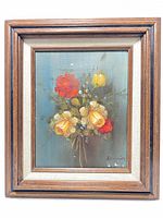 Front view of the vintage floral painting showing red and yellow roses, smaller white flowers, and the artist's signature in the lower right corner, all within the walnut frame.