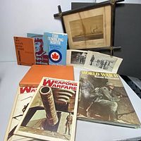 All history books and framed print with wartime photos arranged on table