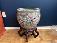 Front view of porcelain planter on rosewood stand against dark wall