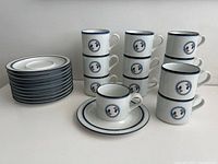 Set of 12 cups and 12 saucers arranged in stacks and pairs, showing full set and pattern.