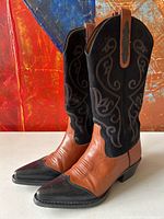Pair of women's western boots showing front and side angles, featuring cognac leather foot, black textured toe cap, and black suede shaft with embroidery.